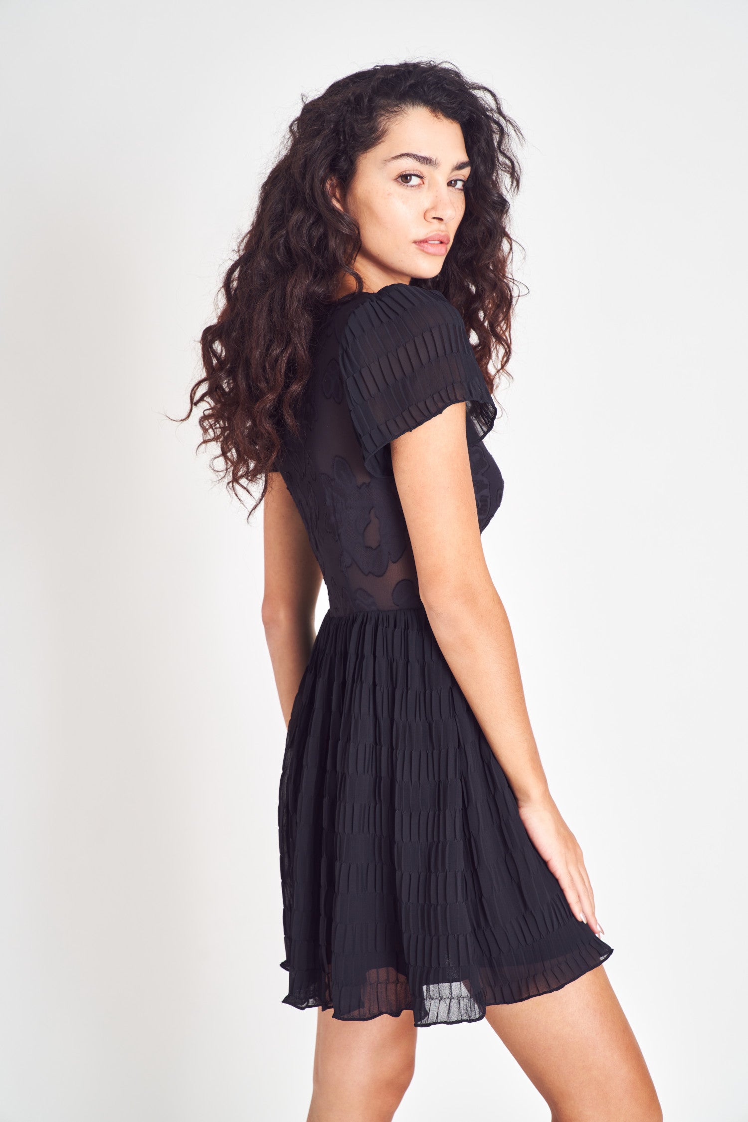 Black short flutter sleeves wrap mini dress with floral jacquard and contrasting pleated texture.