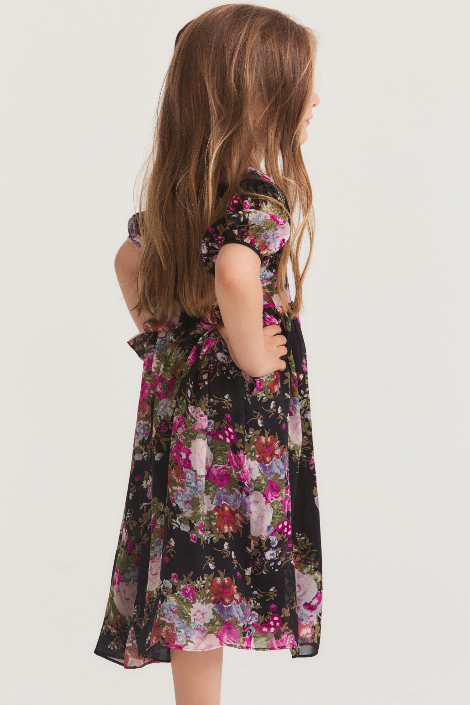 Little girl wearing short sleeved black dress with floral pink pattern