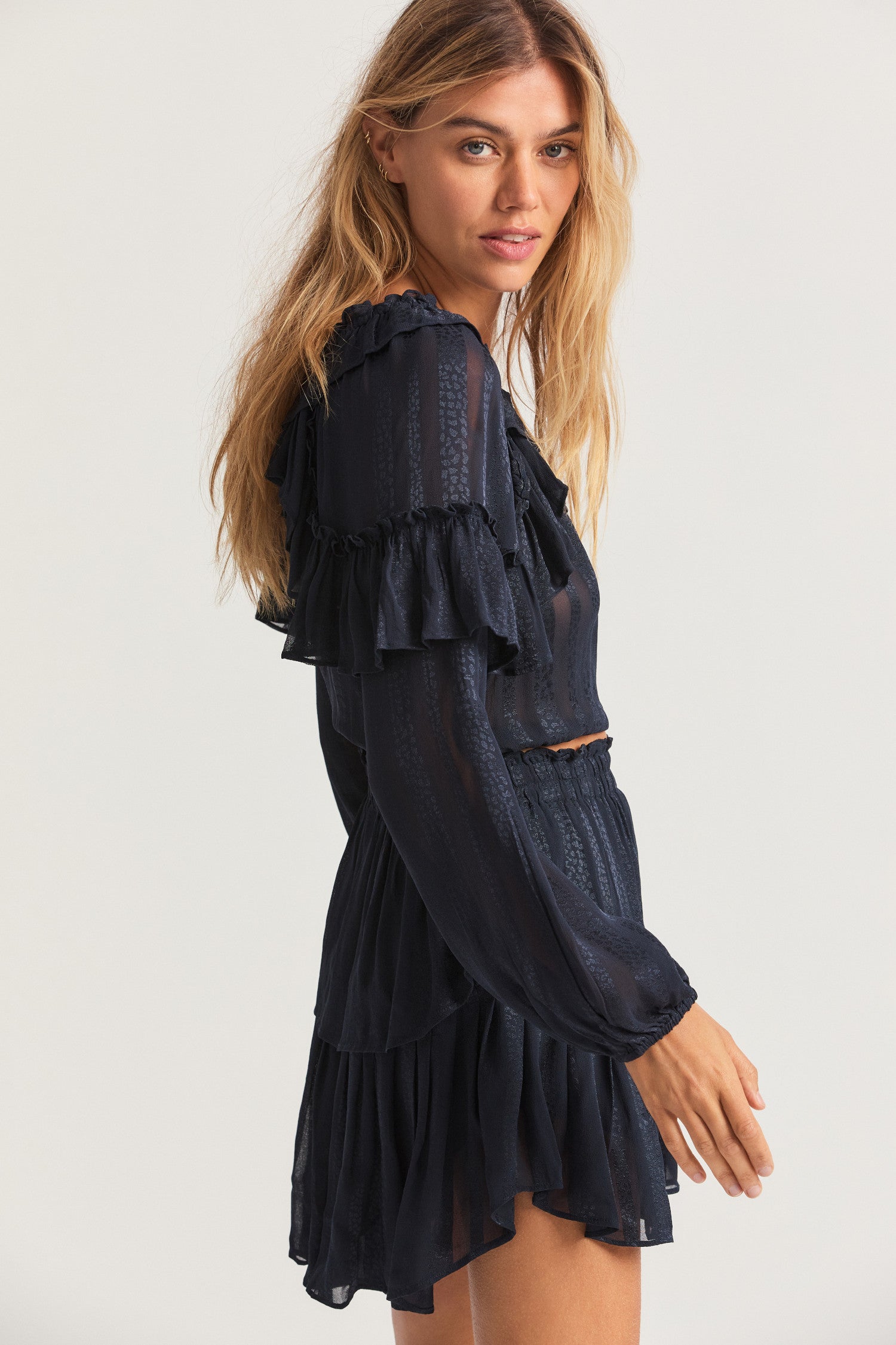 Black long sleeved-top features a striped jacquard fabric, dramatic ruffles all over, an elasticated waist, elastic at the sleeve openings, and a fully functioning center front slit.