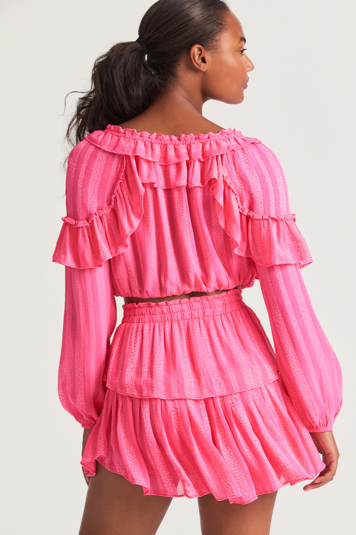 Pink long sleeved-top features a striped jacquard fabric, dramatic ruffles all over, an elasticated waist, elastic at the sleeve openings, and a fully functioning center front slit.