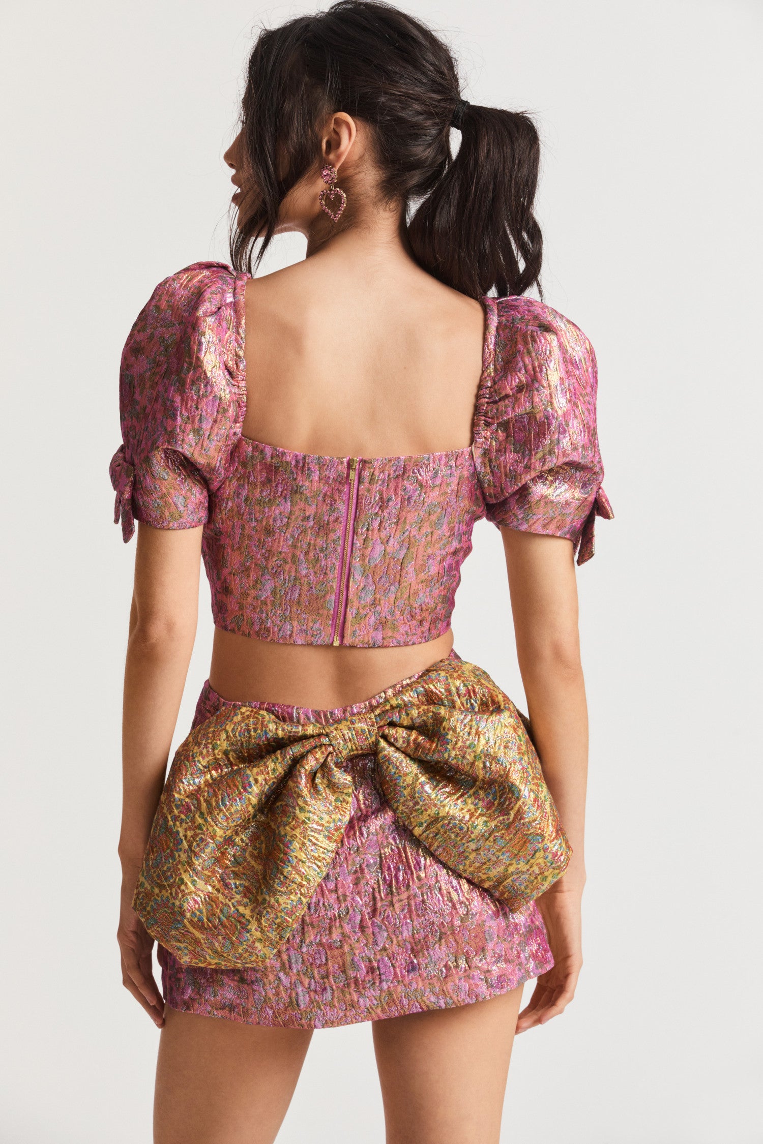  Pink ultra crop top with textural crocheted fabric with and floral print. Puffy sleeves with elastic at the shoulder opening, tiny bows at the sleeves opening, and an exposed zipper at the back bodice. 