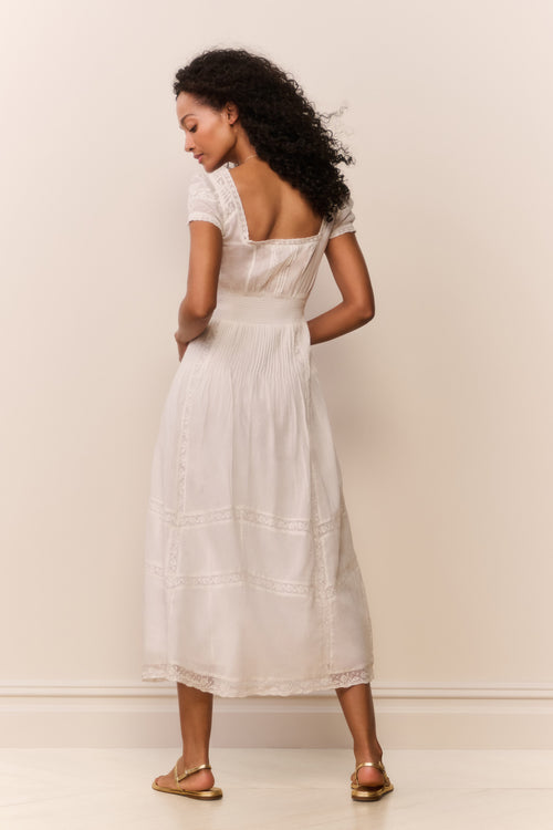 Woman wearing a white dress against a plain background