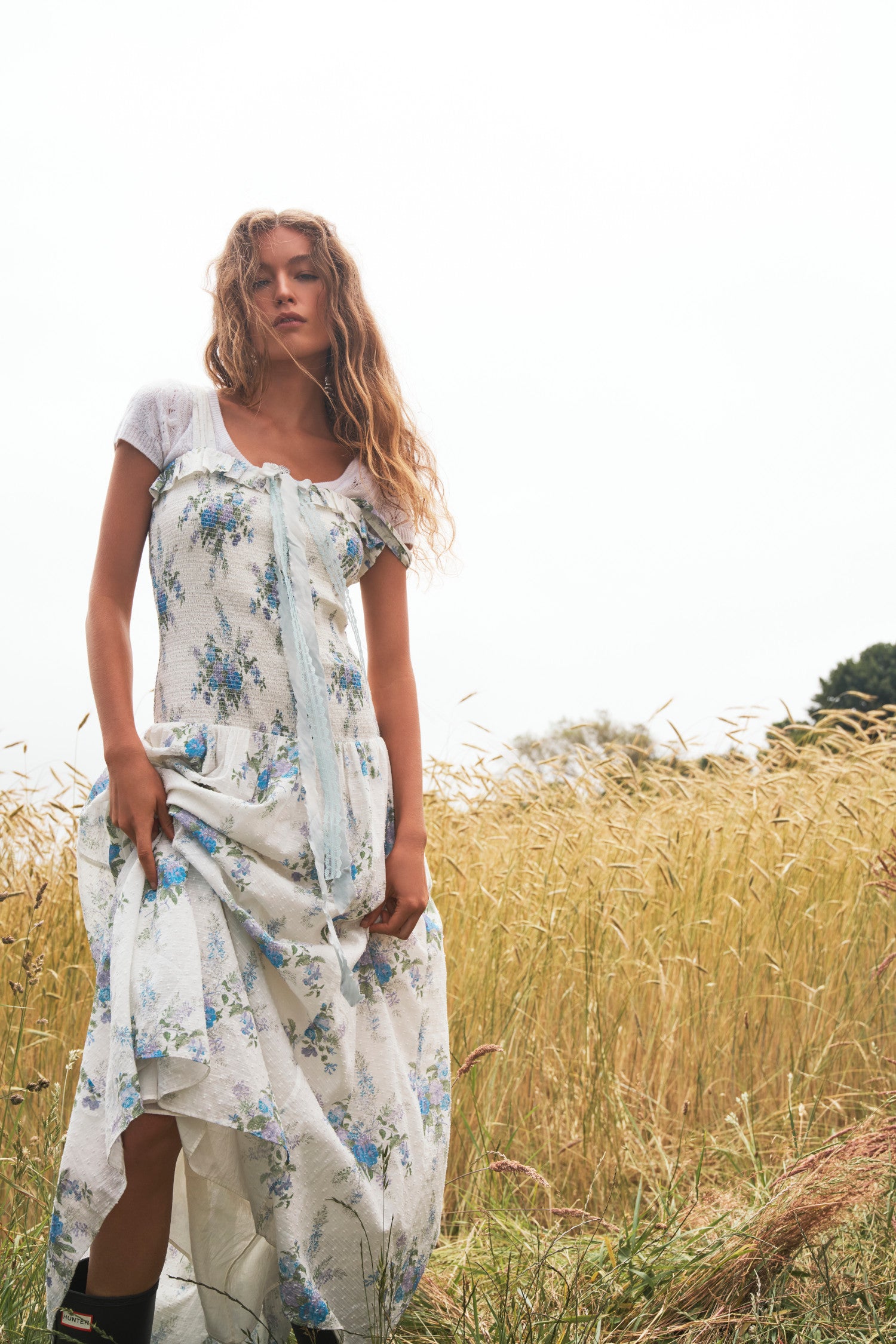 White Maxi dress with a blue heirloom bouquet print on a soft textured dot cotton fabric and a smocked bodice that releases into a sweeping A-line skirt.
