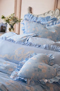 Blue floral bedding set with ruffled edges on a bed.