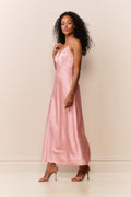 Woman wearing a pink satin white lace trim slip dress against a plain background