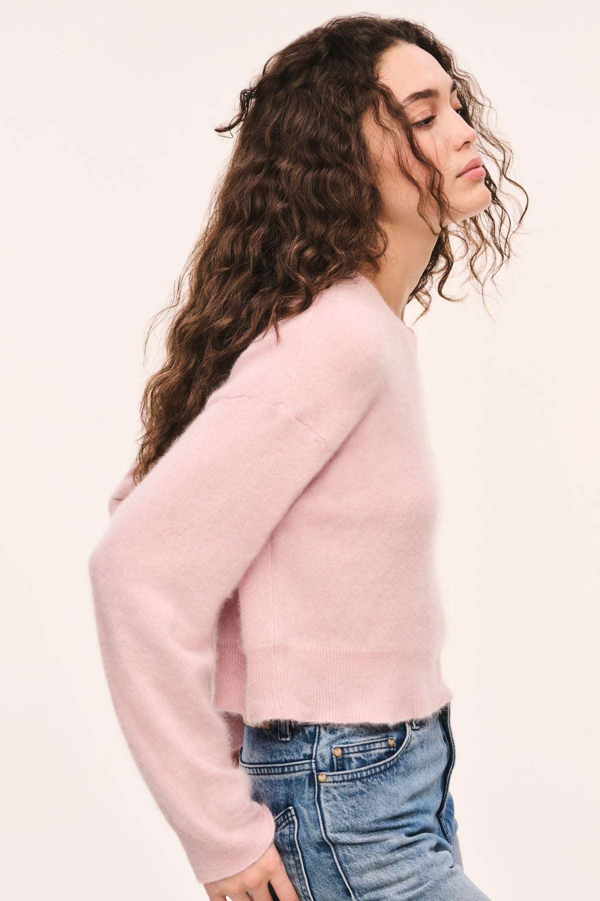 Pink crewneck knit pullover, long sleeves with ribbed cuffs, side view