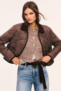 Front view of brown quilted jacket with dark brown corduroy collar and corduroy trim, snap button front, and front pockets with velvet bow trim, shown with jacket open
