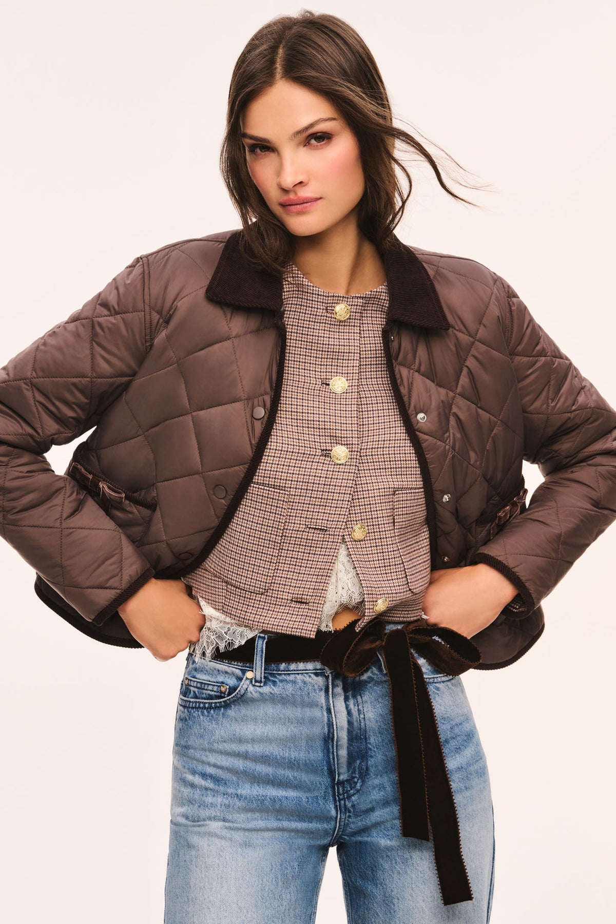 Front view of brown quilted jacket with dark brown corduroy collar and corduroy trim, snap button front, and front pockets with velvet bow trim, shown with jacket open