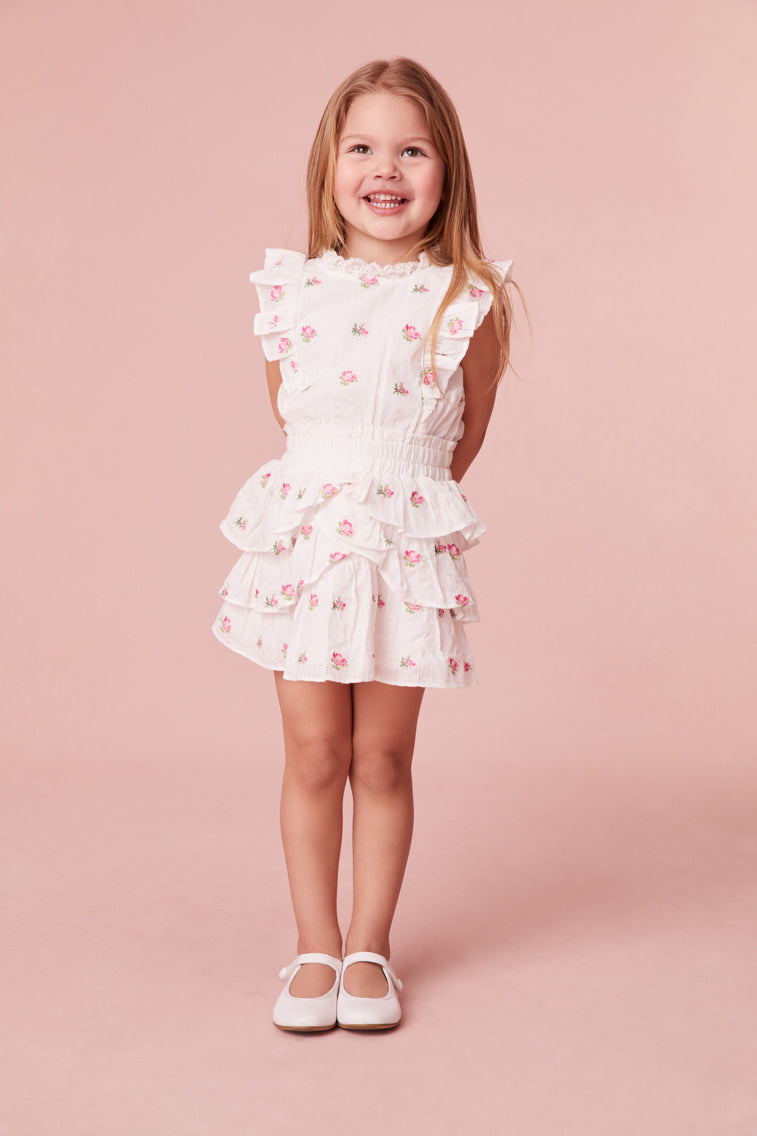 Pink floral embroidered frock with a ruffle-trimmed collar, buttons down center front, flutter sleeves, an elastic waist and overlapping asymmetrical ruffles at the skirt.