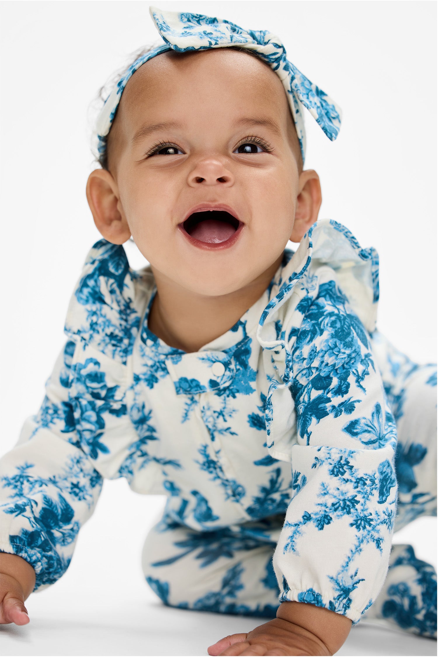 Model wearing Baby's blue floral onesie with matching headband