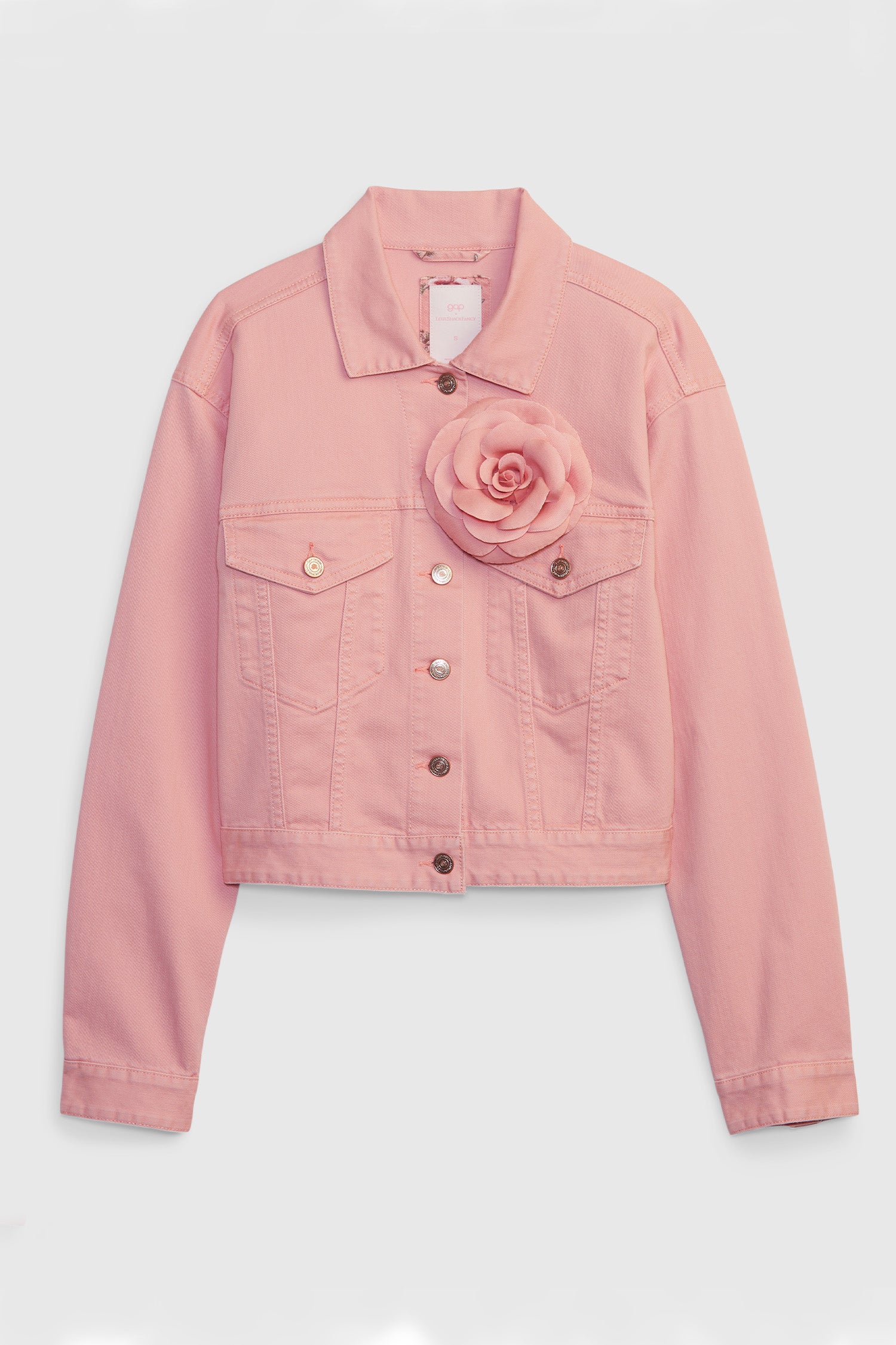 Model wearing pink denim jacket with rosette on chest