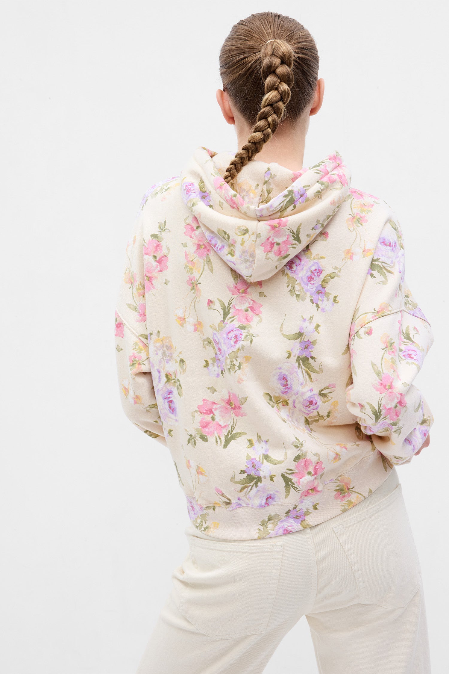 Back image of model wearing cream floral hoodie with GAP arch logo on chest and pink, purple, and green floral print