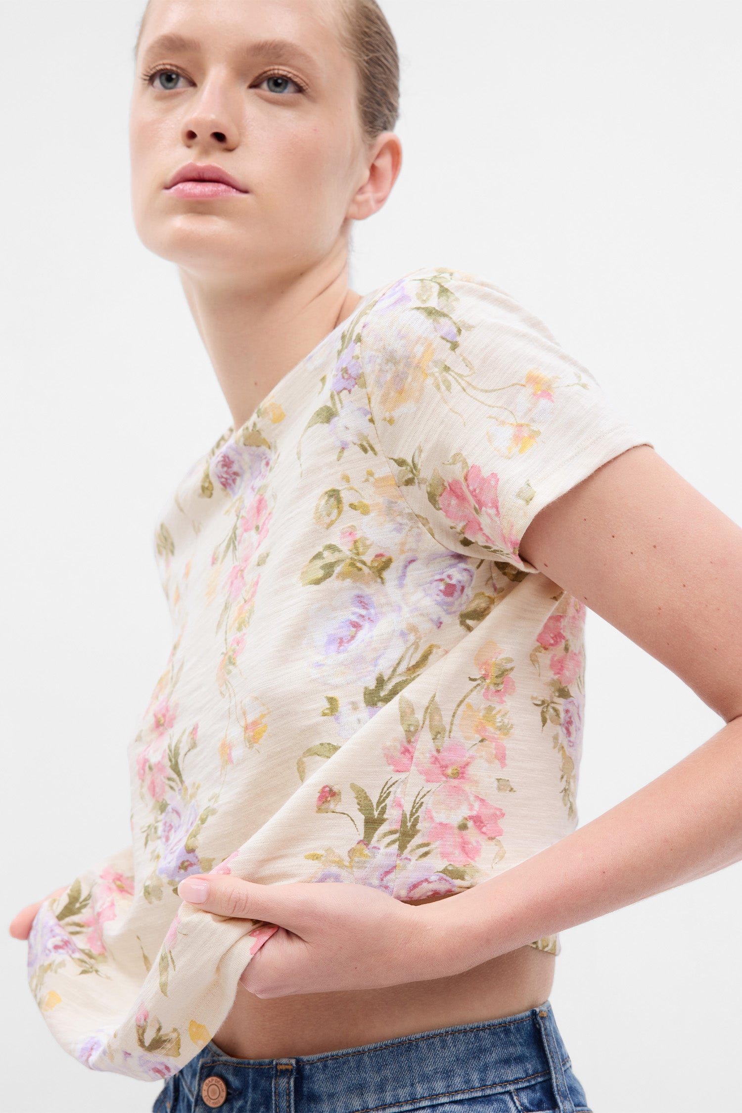 Model wearing cream floral t-shirt with pink, purple, yellow, and green floral print