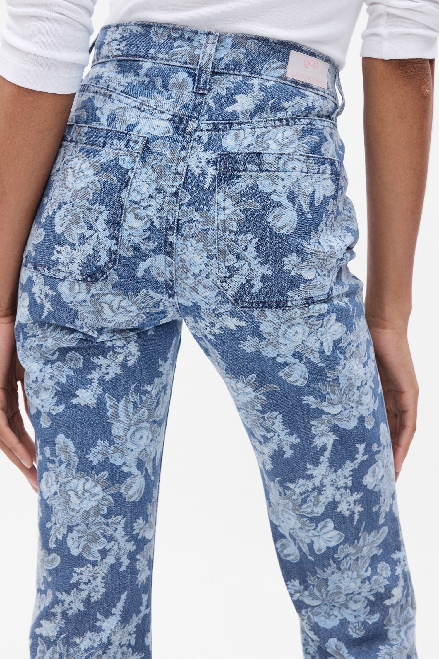 Back image of model wearing blue floral high rise flare jeans with pockets at the back.