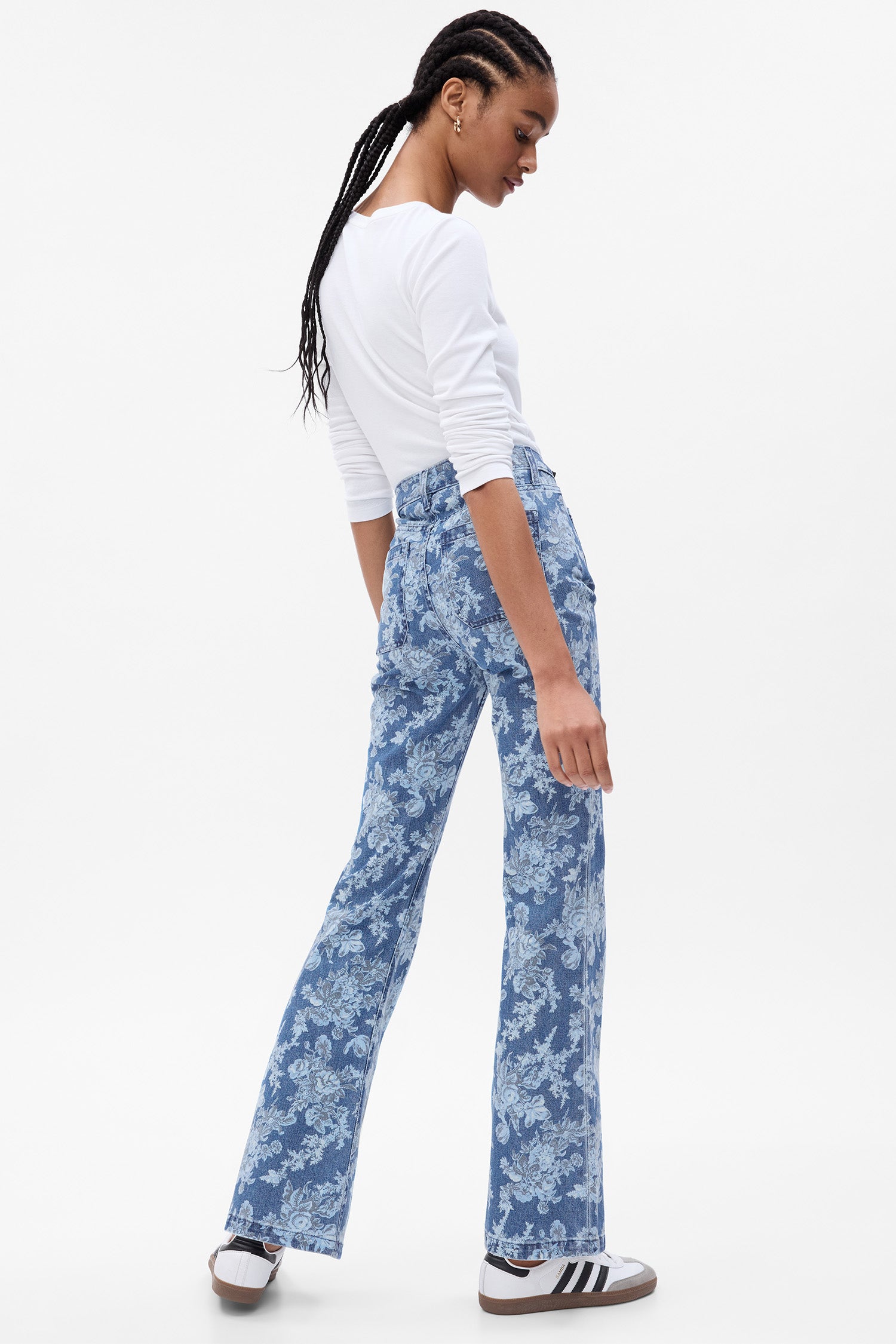 Side image of model wearing blue floral high rise flare jeans that hit at the ankle