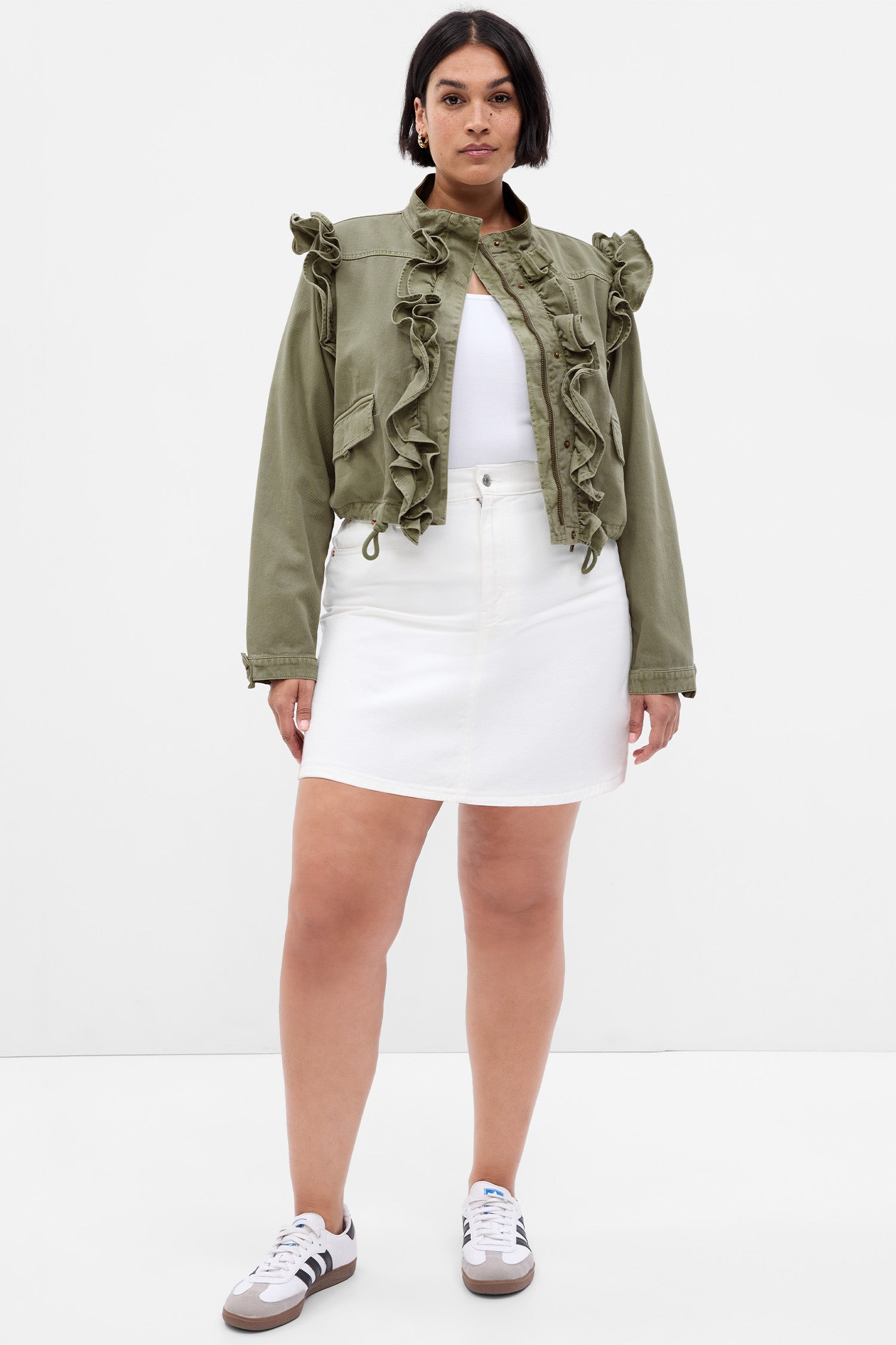 Model wearing green crop utility jacket with ruffle detail along zipper and shoulders. 
