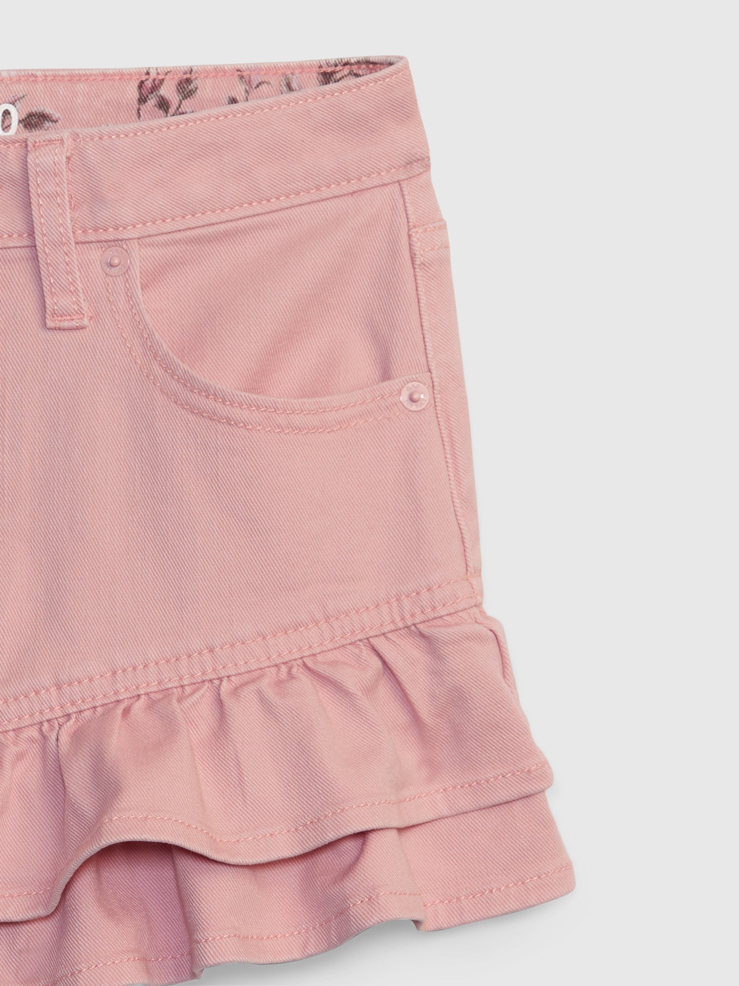 Close up image detailing kids pink denim mini skirt with ruffle hem