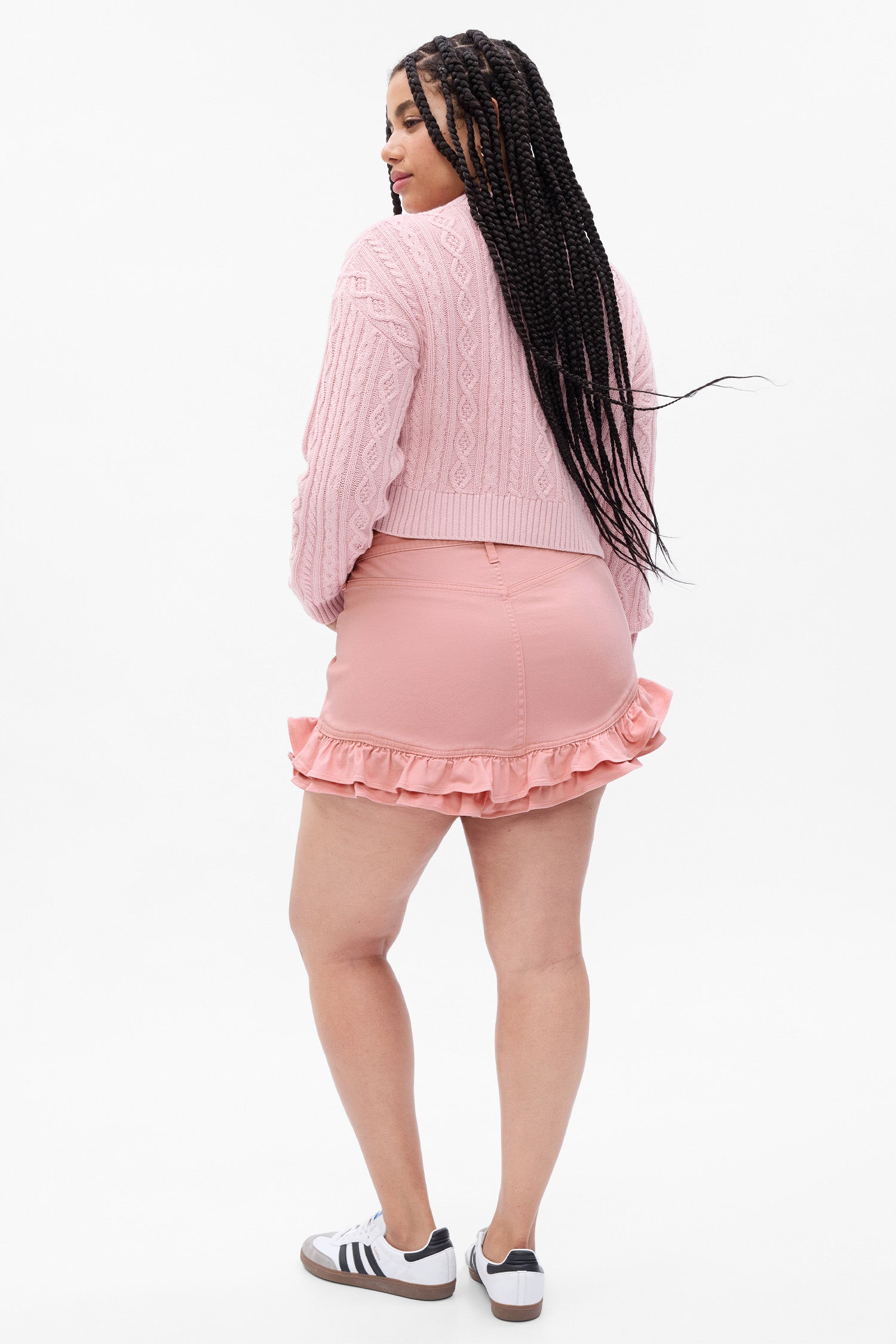 Back image of model wearing pink denim mini skirt with ruffle detail at hem