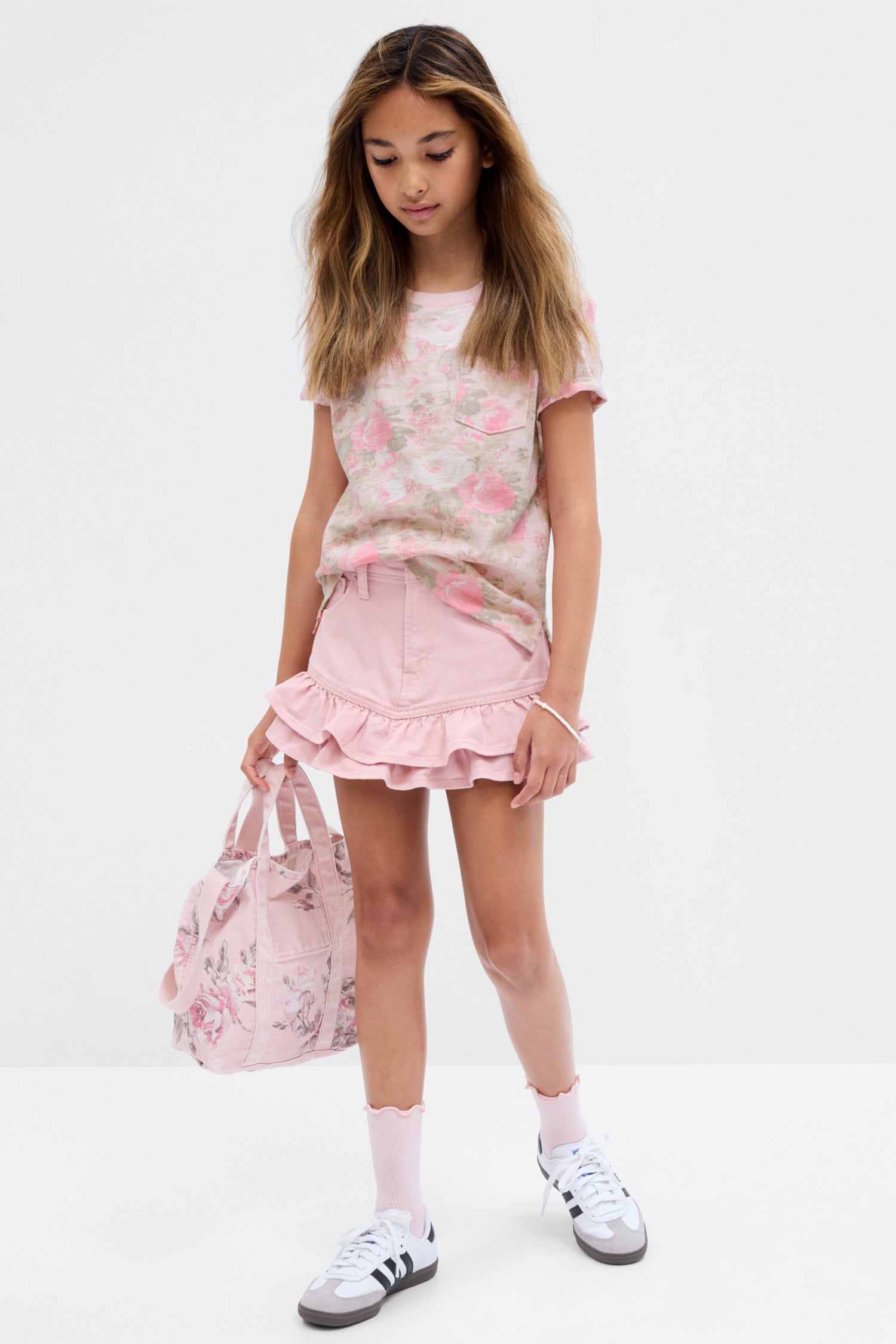Model wearing kids pink denim mini skirt with ruffle hem