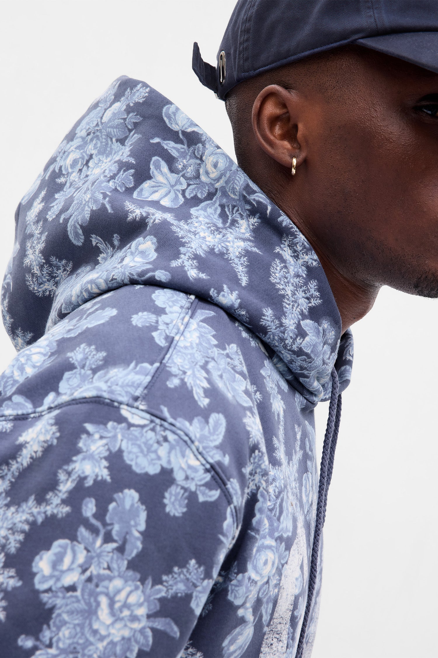 Close up image detailing blue floral pattern and hood on men's hoodie