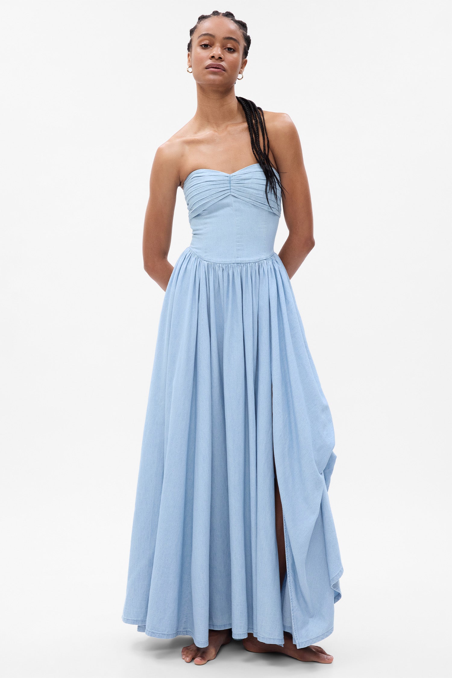 Model wearing blue denim strapless maxi dress with corset top and tiered skirt