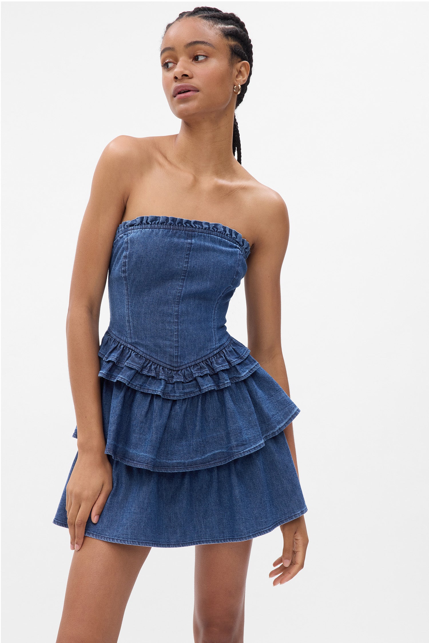 Model wearing blue denim mini dress with corset top and ruffle skirt