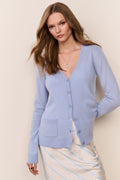 Woman wearing a light blue cardigan over a striped skirt set against a beige background