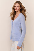 Woman wearing a light blue cardigan over a striped skirt set against a beige background