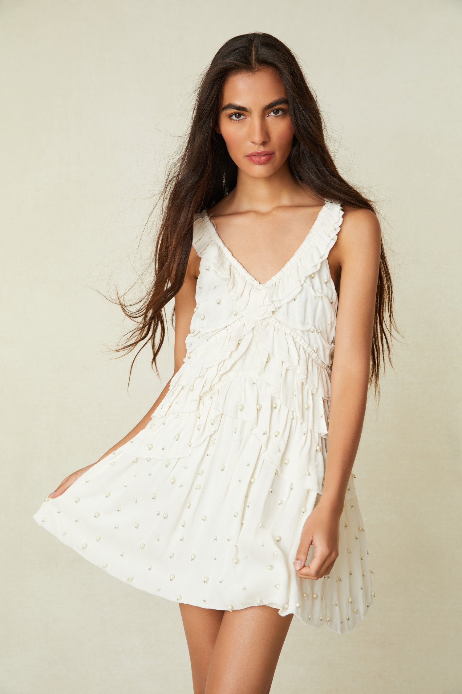 White Mini Dress This must-have mini is all hand-beaded with iridescent pearls fastened by crystal prongs on a soft polyester satin fabric. The dress begins with a low, round neckline that falls to tiers of ruffles with asymmetrical zipper.