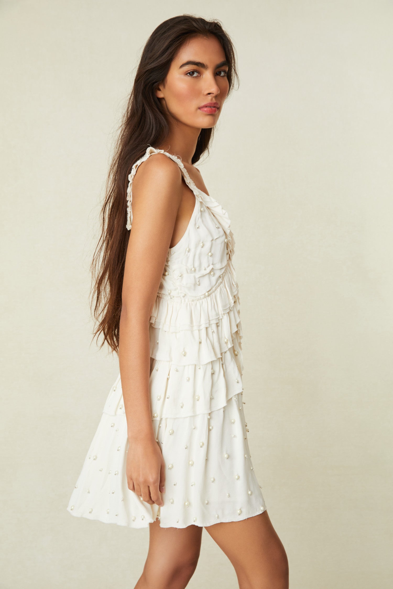 White Mini Dress This must-have mini is all hand-beaded with iridescent pearls fastened by crystal prongs on a soft polyester satin fabric. The dress begins with a low, round neckline that falls to tiers of ruffles with asymmetrical zipper.