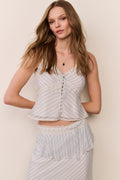 woman wears striped camisole with lace details and matching skirt against beige background.