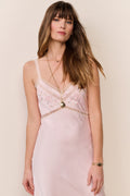 woman wears pink silk gown with lace detailing against beige background