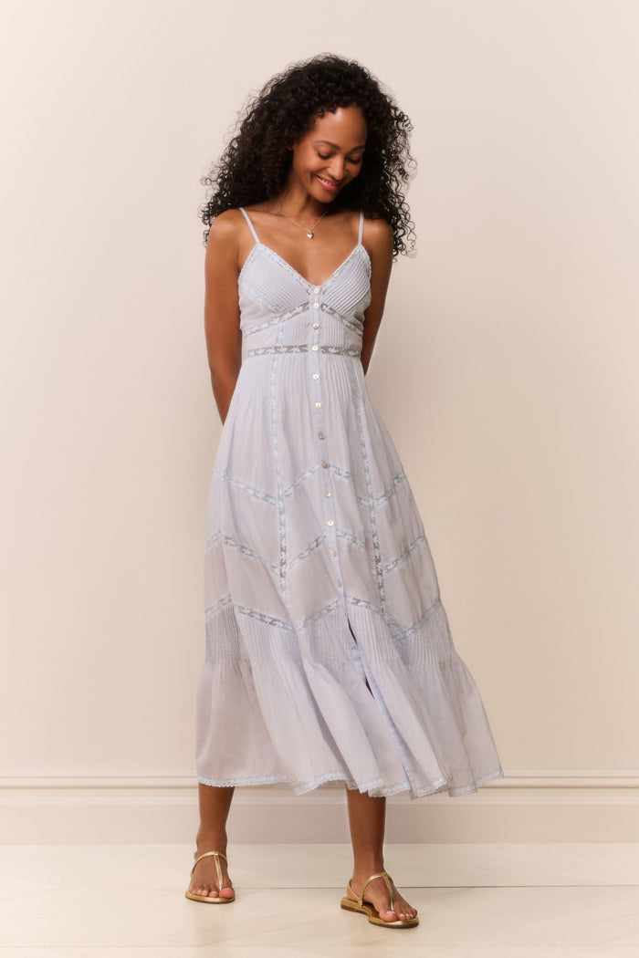 Woman wearing a blue lace dress against a plain background