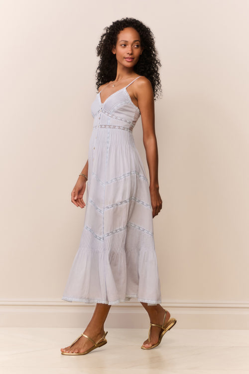 Woman wearing a blue dress with thin straps against a plain background