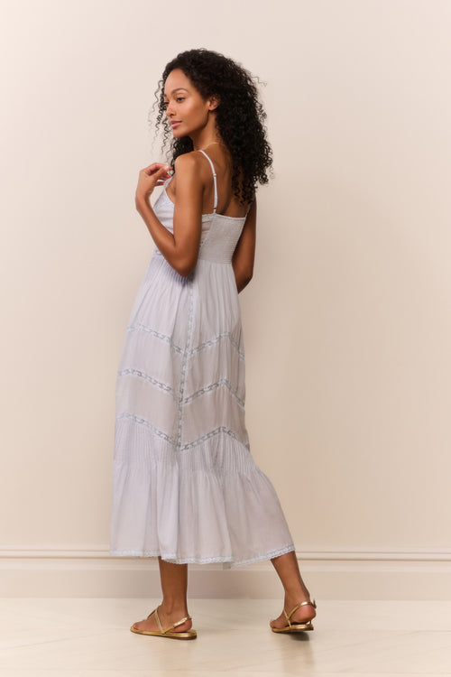 Woman wearing a blue dress with thin straps against a plain background