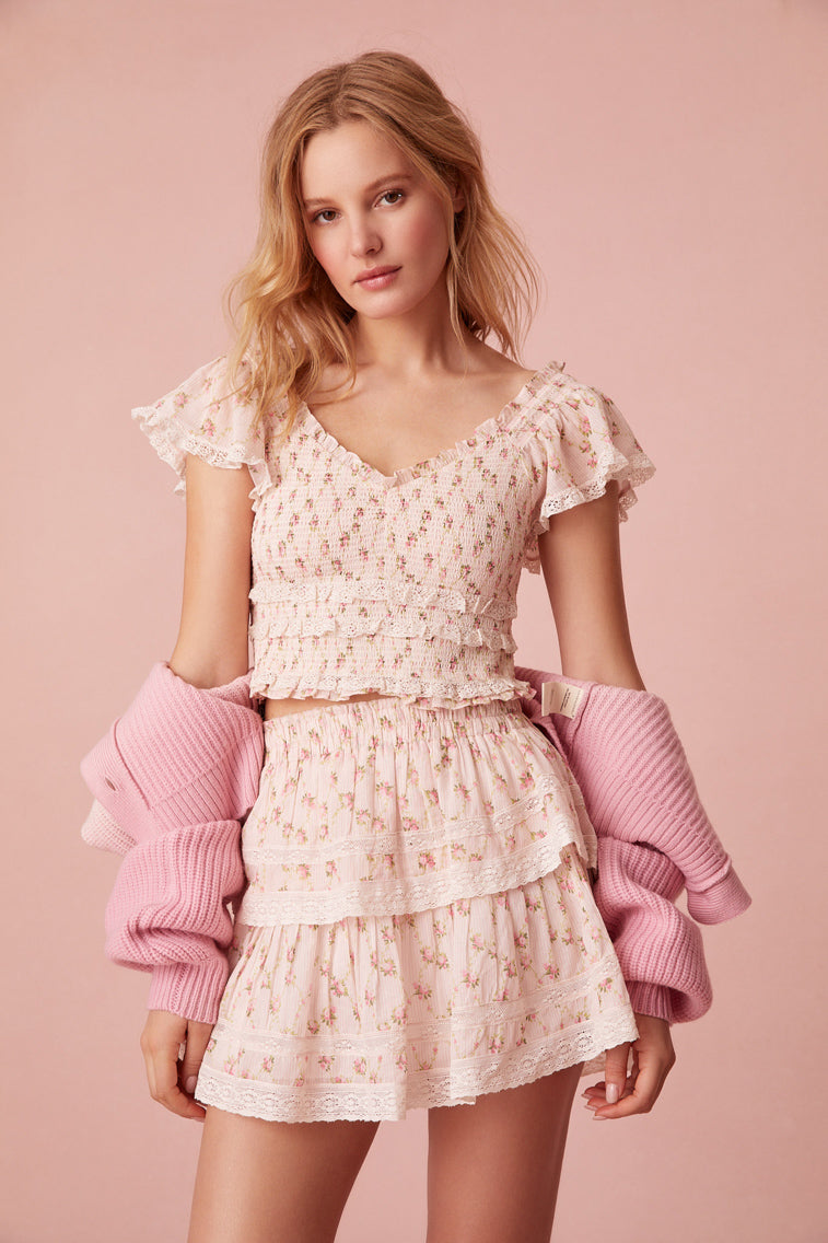 Slightly cropped, the top features short puff sleeves with lace trimming, a sweetheart neckline, and a smocked bodice.