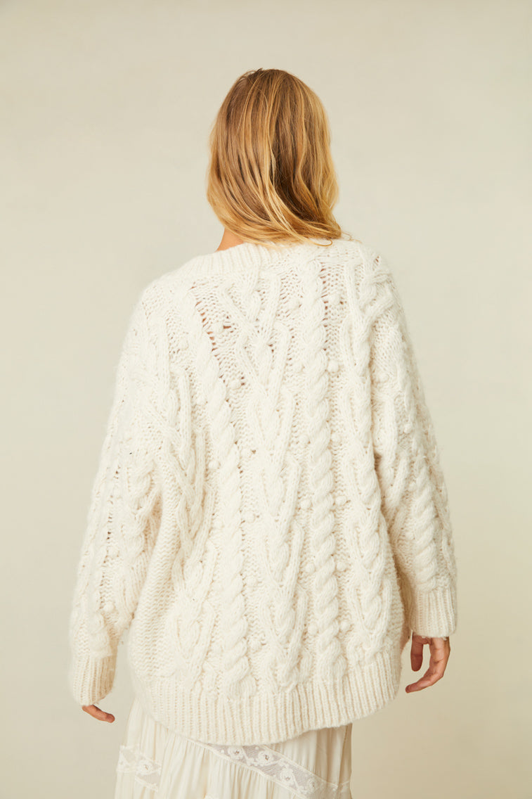 Hand-knitted sweater that features four buttons at center front, and cable stitching mixed with bobble stitch.