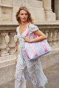 Woman holding a patterned tote bag in front of classical architecture