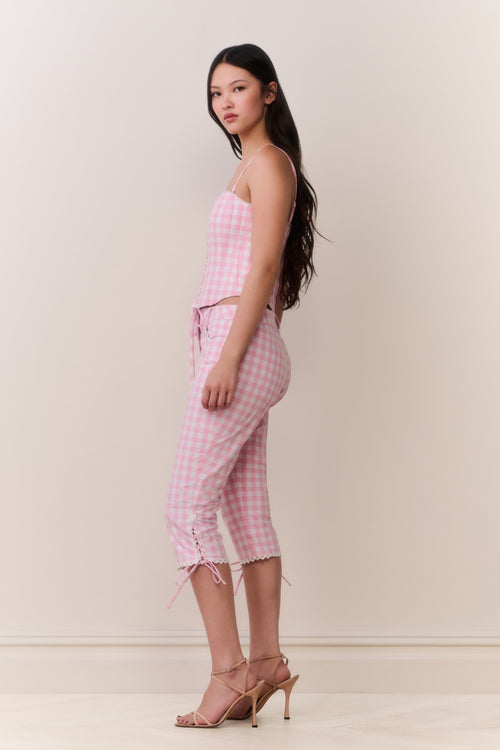 Woman wearing a pink gingham corset top and matching capris against a white background 