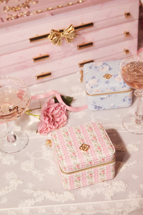 Decorative jewelry box with floral patterns on a table with glasses of pink champagne and a pink bow.