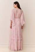 Woman wearing a pink floral dress with sheer sleeves against a white background