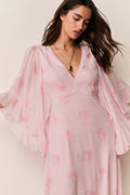 Woman wearing a pink floral dress against a plain background