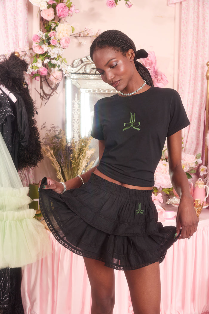 Woman wearing a black outfit with green logo in a decorated room.