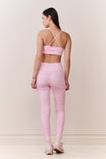 Woman wearing a pink sports bra and leggings set on a plain background