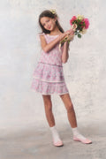 Young girl in a pink floral dress holding flowers against a light background