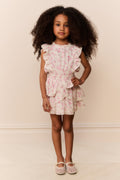 Young girl wearing a floral dress with ruffles from on a plain background