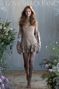Woman in a beige suede mini dress standing between floral arrangements with 'LOVE SHACK FANCY' branding.