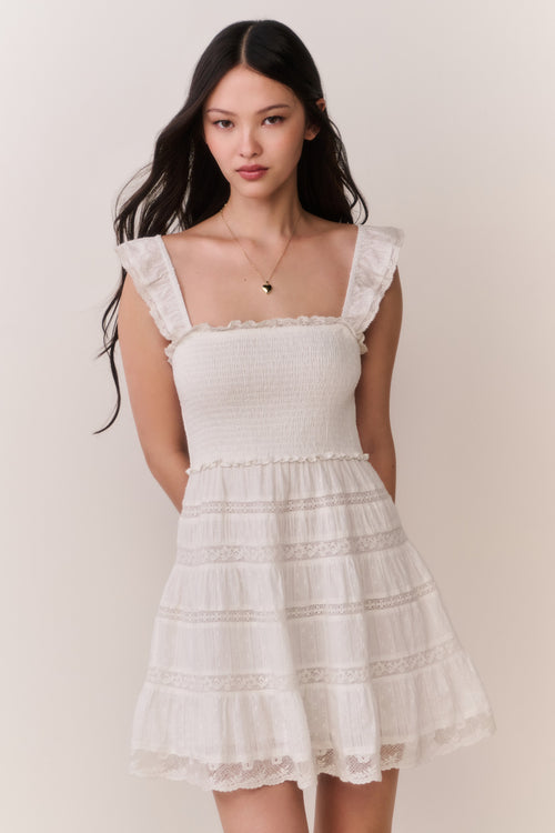 Woman wearing a white ruffle dress against a plain background