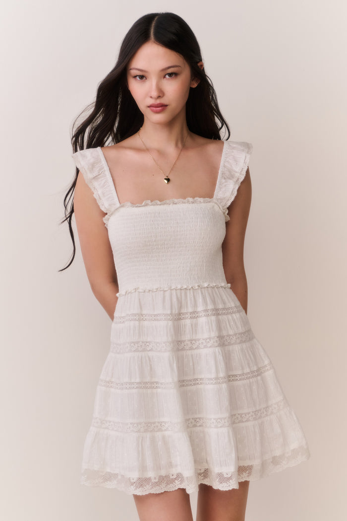 Woman wearing a white ruffle dress against a plain background