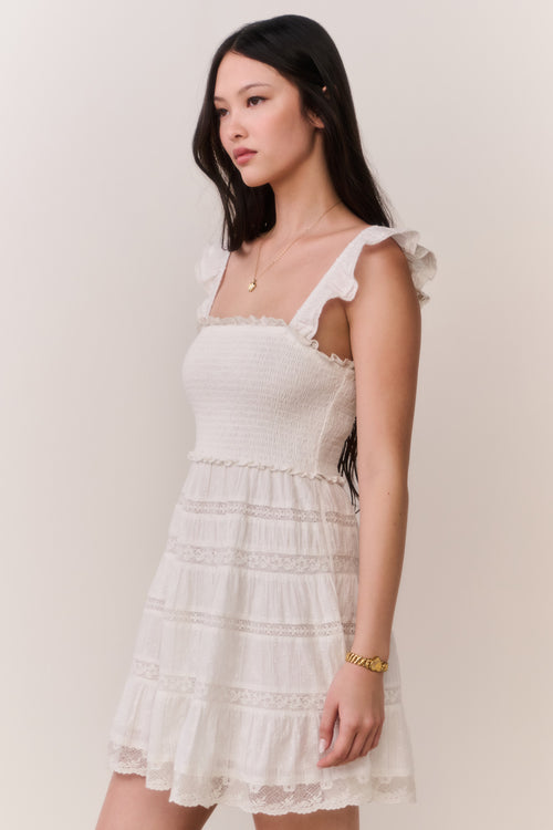 Woman wearing a white ruffle dress against a plain background
